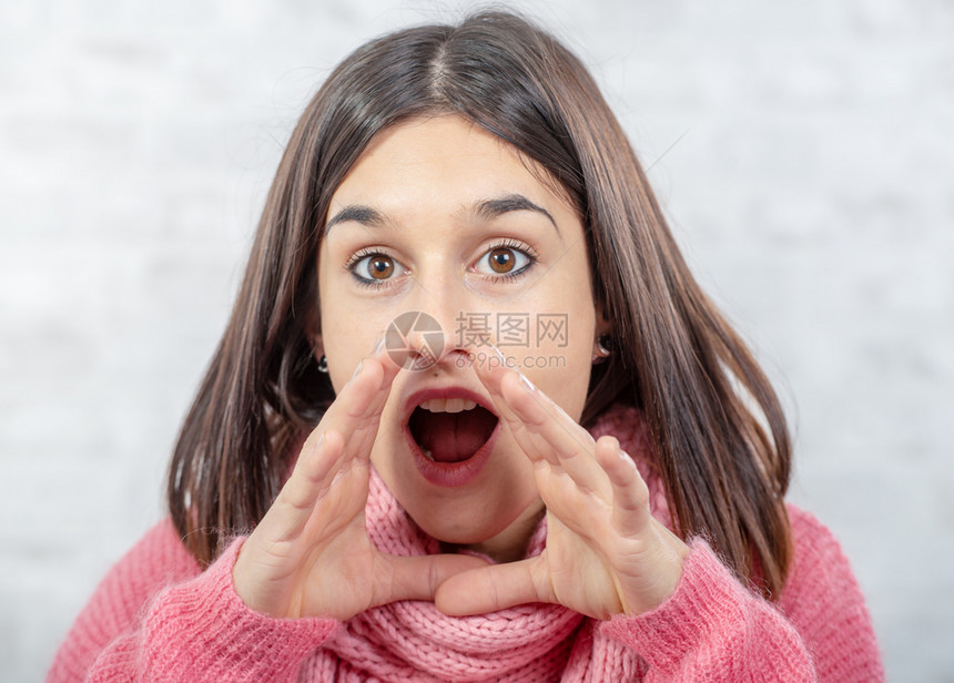 一个漂亮的年轻黑发女人用手围着她的嘴张图片