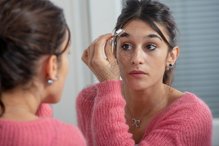 一个年轻的黑发女人在镜子里化妆背景图片