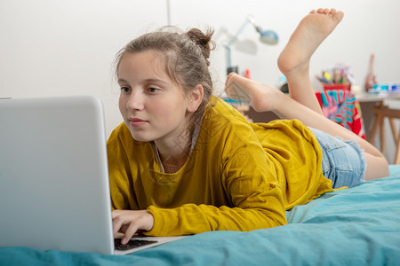 少女躺在床上用笔记本电脑图片