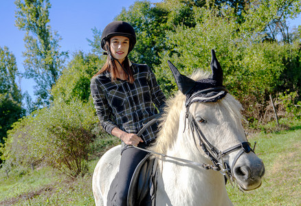 带着黑头盔的年轻女子骑着白马图片