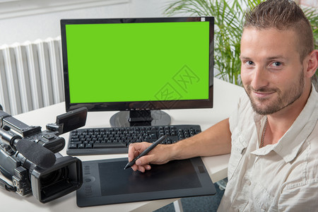 一名男子视频编辑配有图形平板电脑和专业摄像头绿色屏幕图片