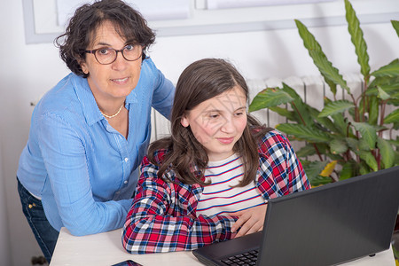 母亲和女儿在家使用笔记本电脑图片