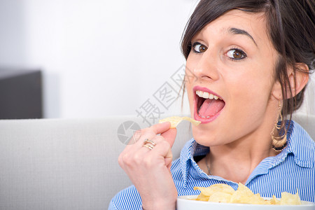 美丽的年轻黑发女吃薯片图片