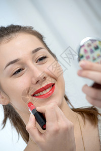 年轻和微笑的女人涂口红图片