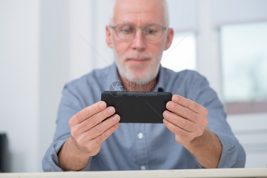 一个成熟的英俊男人在家里使用智能手机图片