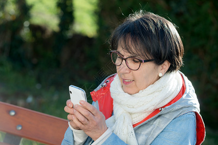 在户外使用智能手机的成年黑发女人图片