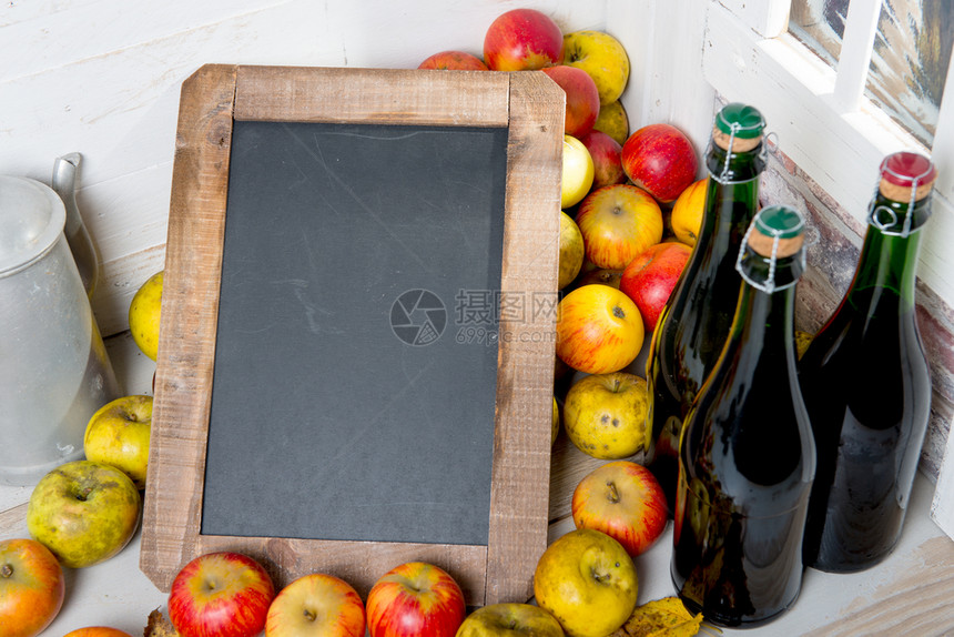 有机新鲜苹果和一瓶带有黑板的诺曼底苹果酒图片