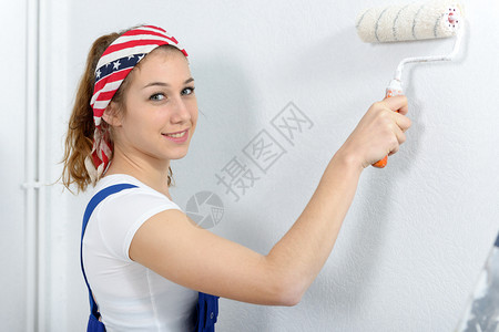 一个漂亮的年轻女人涂着墙上的白色图片