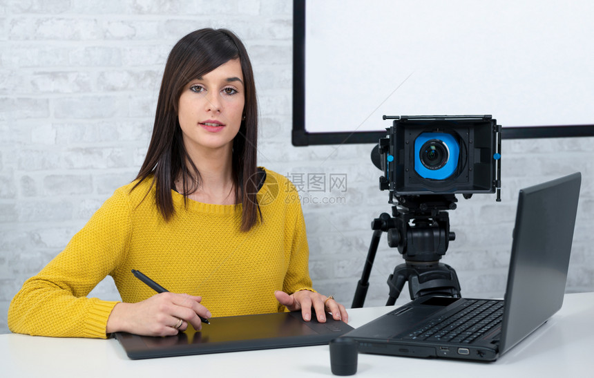 一名使用图形平板电脑进行视频编辑的年轻女录像师图片