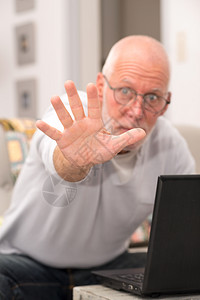 一个愤怒的老人在家里用笔记本电脑背景图片