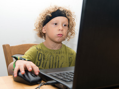 一个小金发男孩用笔记本电脑图片