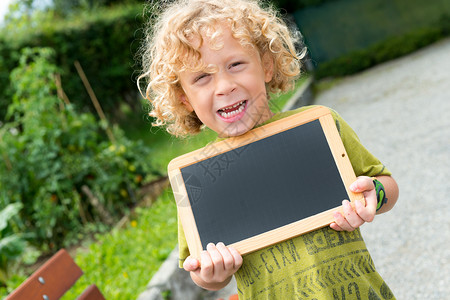 一个金发小男孩拿着黑板图片