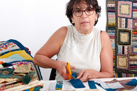 一个成熟的黑发女人切织布缝纫杂工图片