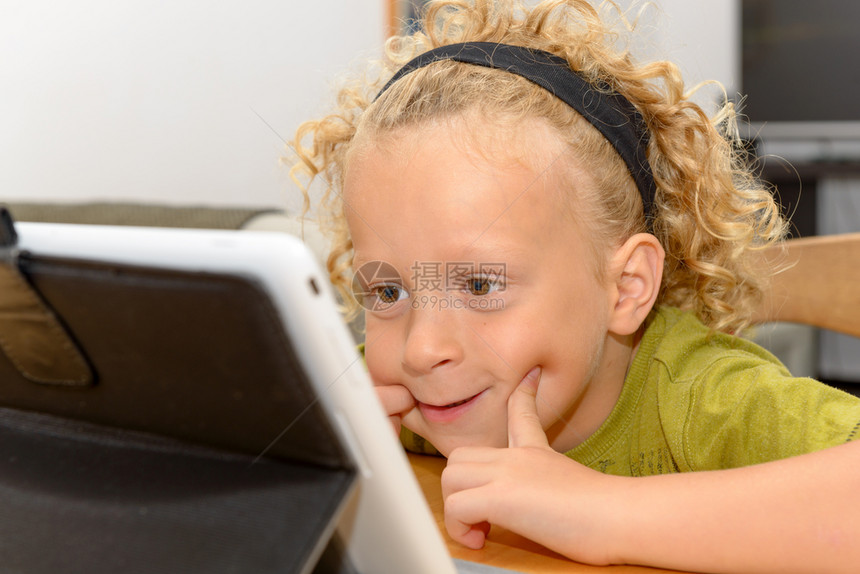 一个金发小男孩在桌上玩电脑图片