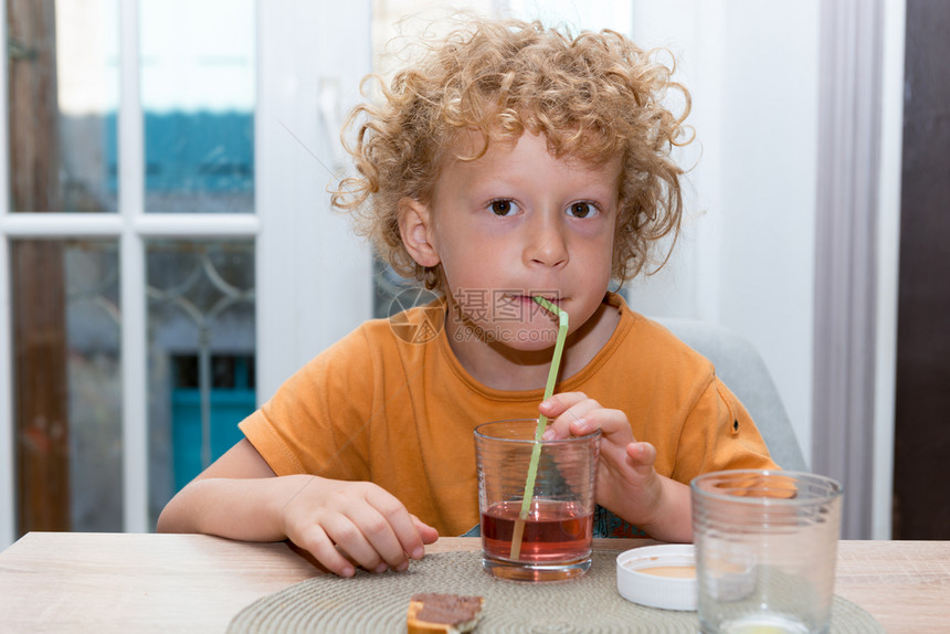 一个可爱的小男孩喝红果汁用稻草图片