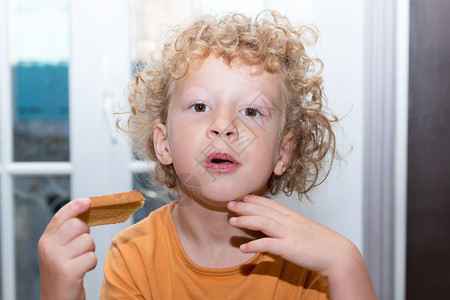 一个金发小男孩早上吃面包图片