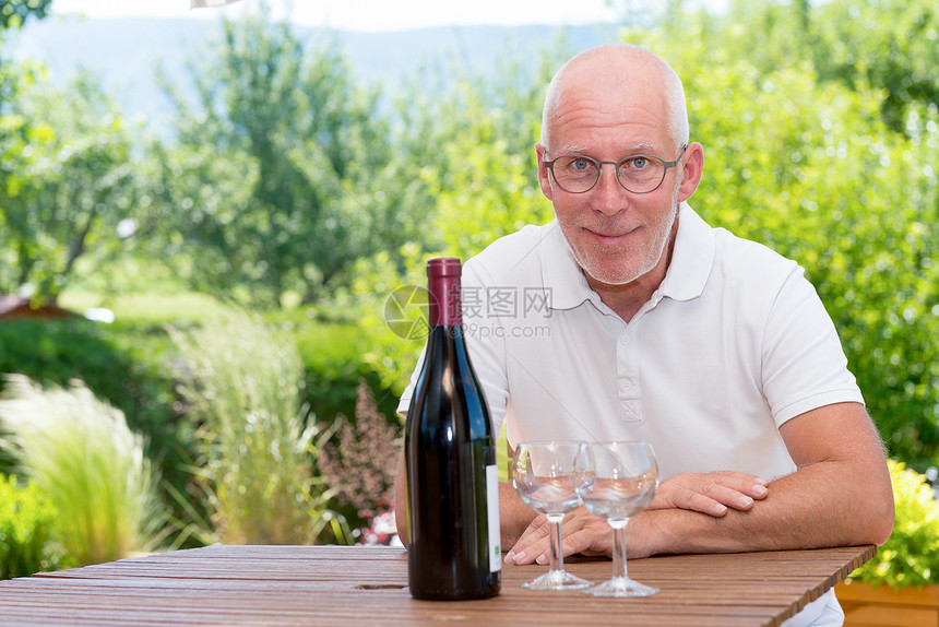 在阳台上拿着一瓶红酒的男子图片