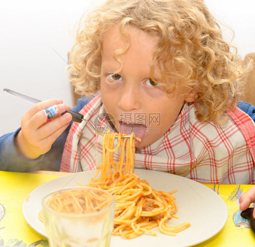 一个金发小男孩吃意大利面加番茄酱图片