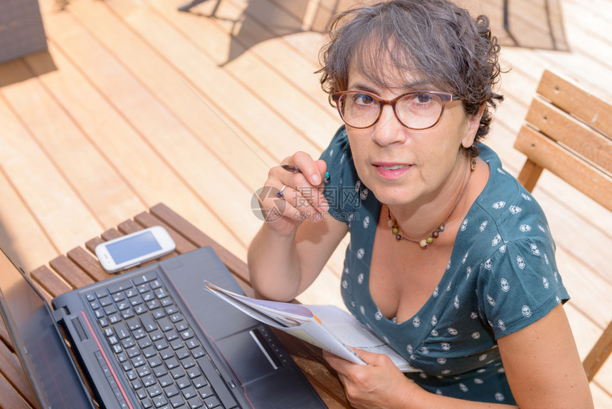 现代临时成年妇女用笔记本电脑坐在露天花园图片