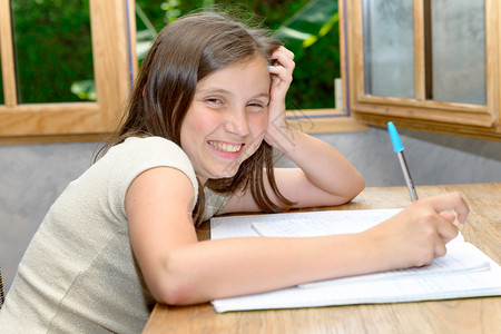 一个年轻笑的少女做家庭作业图片