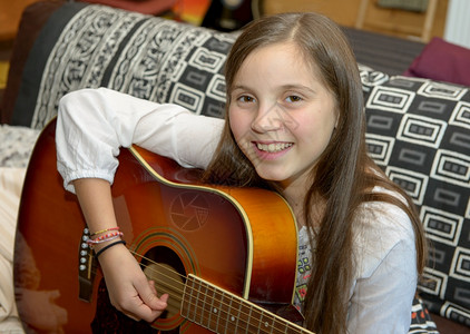 年轻女孩在沙发上弹音吉他背景图片