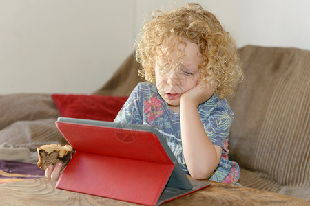 金发小男孩在家里使用平板电脑图片