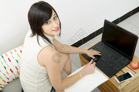 用笔记本电脑坐在沙发上的学生背景图片