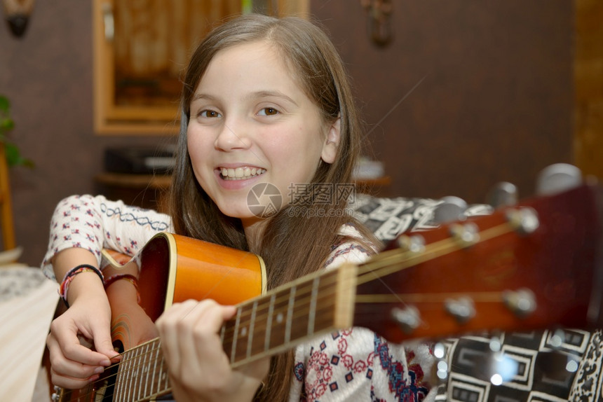 年轻女孩在沙发上弹音吉他图片