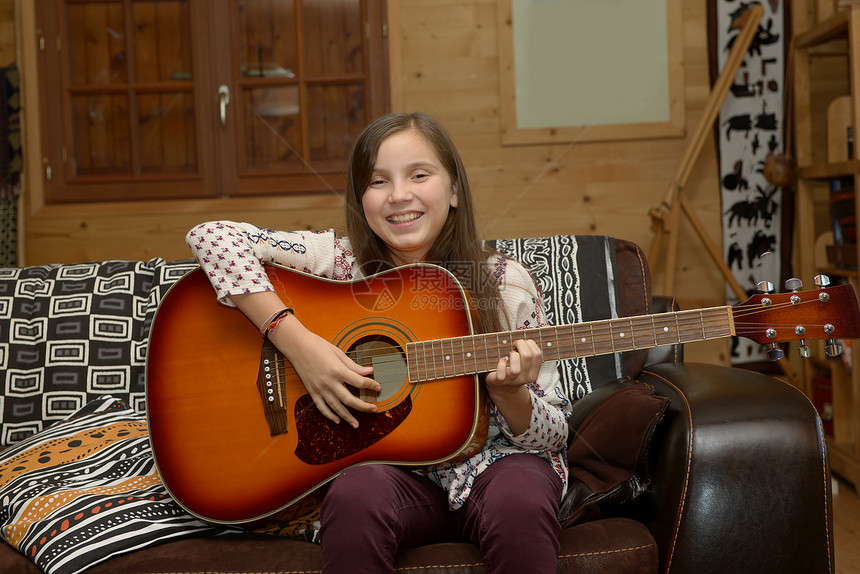 年轻女孩在沙发上弹音吉他图片