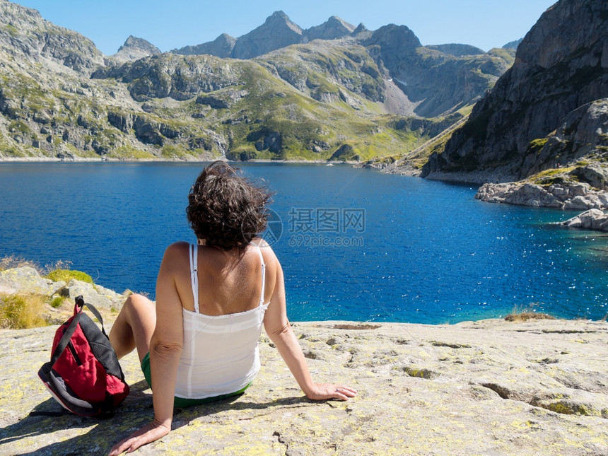 一位妇女远足者躺在法国平原的一个山湖附近图片