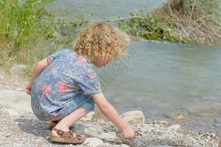一个金发小男孩在水边玩图片