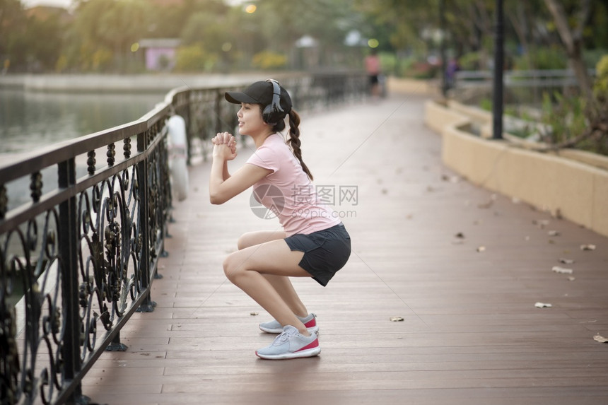 美丽的女人正在公园里听音乐和运动图片