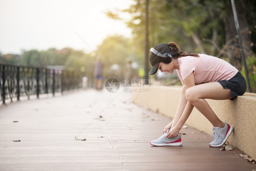 美丽的女人正在公园里听音乐和运动图片