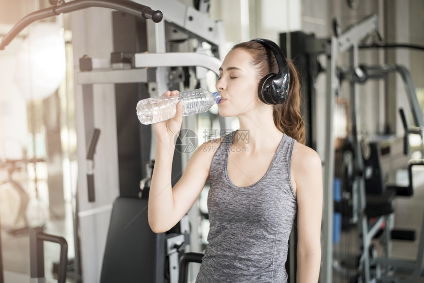 漂亮的年轻运动女子在健身房喝水康生活方式图片
