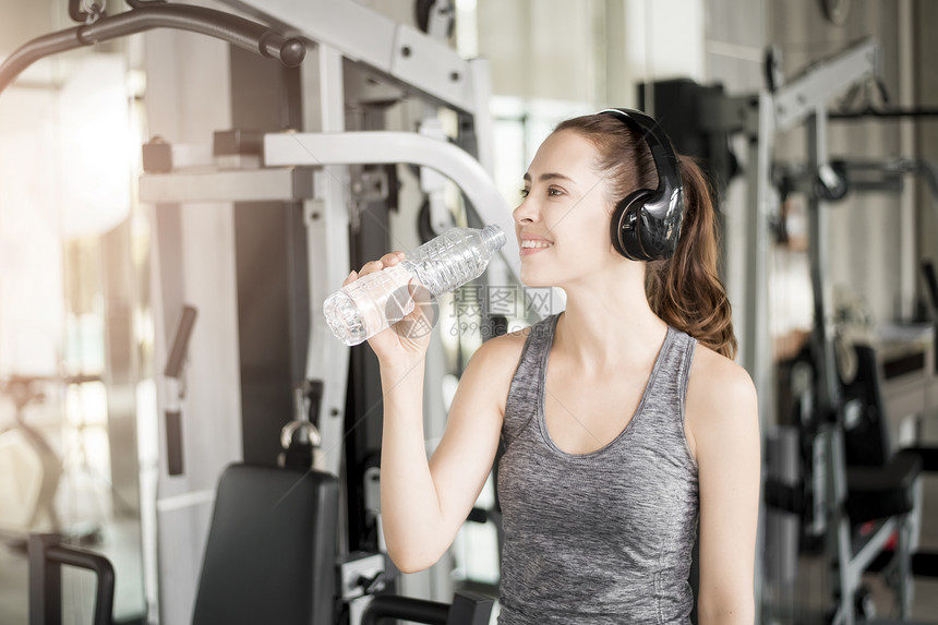 漂亮的年轻运动女子在健身房喝水康生活方式图片
