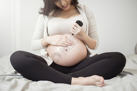 孕妇腹部涂抹乳霜的特写镜头图片
