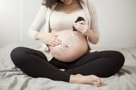 孕妇腹部涂抹乳霜的特写镜头图片