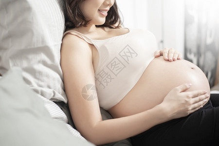 美丽的亚洲孕妇躺在床上抚摸肚子图片