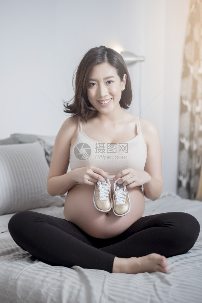 美丽的亚洲孕妇手拿小孩的鞋子图片