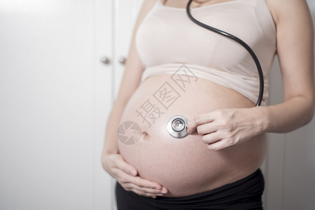 美丽的亚洲孕妇预产期使用听诊器背景图片