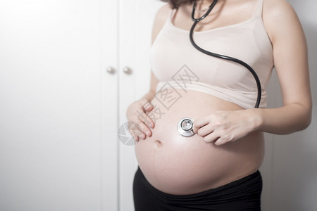 美丽的亚洲孕妇预产期使用听诊器背景图片