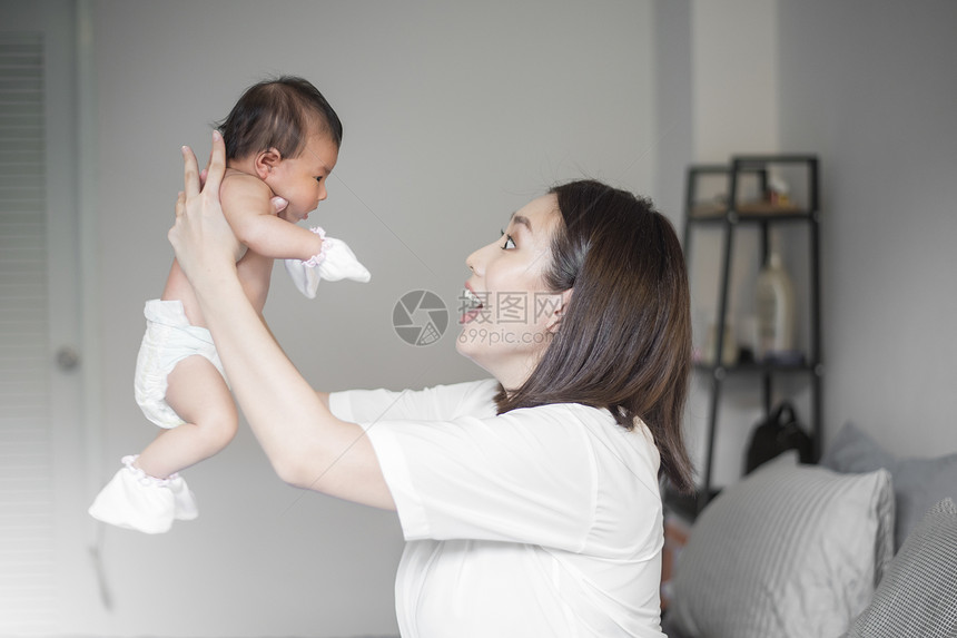 美丽的母亲正在卧室里玩弄她新生的婴儿图片