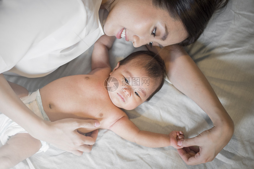 美丽的母亲正在卧室里玩弄她新生的婴儿图片