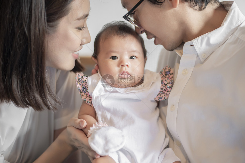 快乐的家庭爸妈和玩着他们可爱的新生婴儿图片