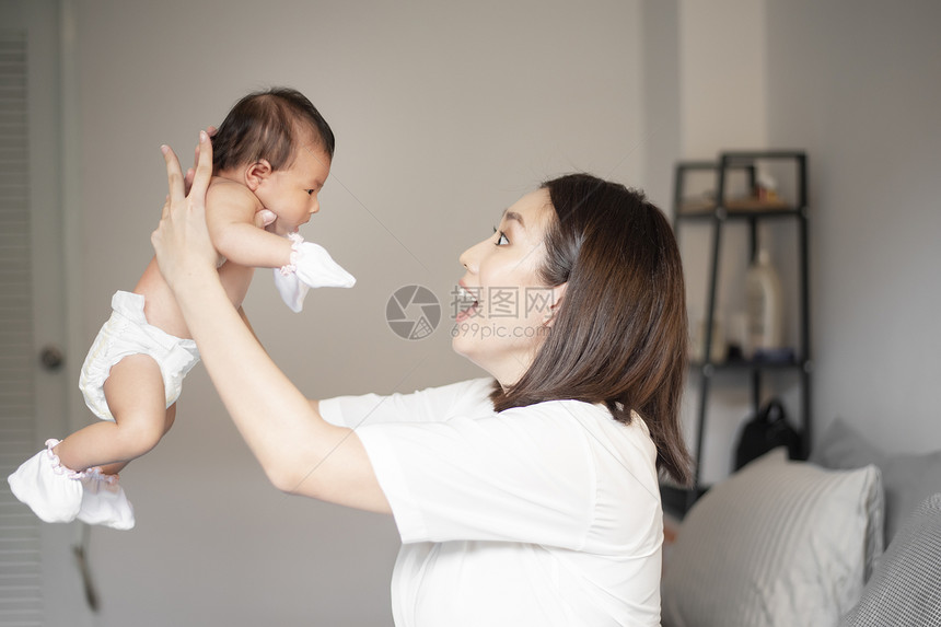 美丽的母亲正在卧室里玩弄她新生的婴儿图片