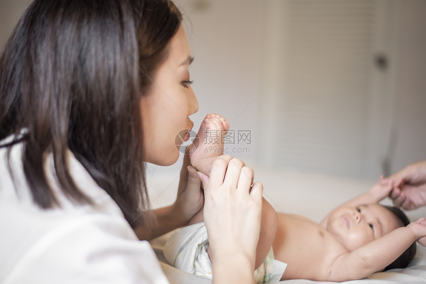 美丽的母亲正在卧室里玩弄她新生的婴儿图片