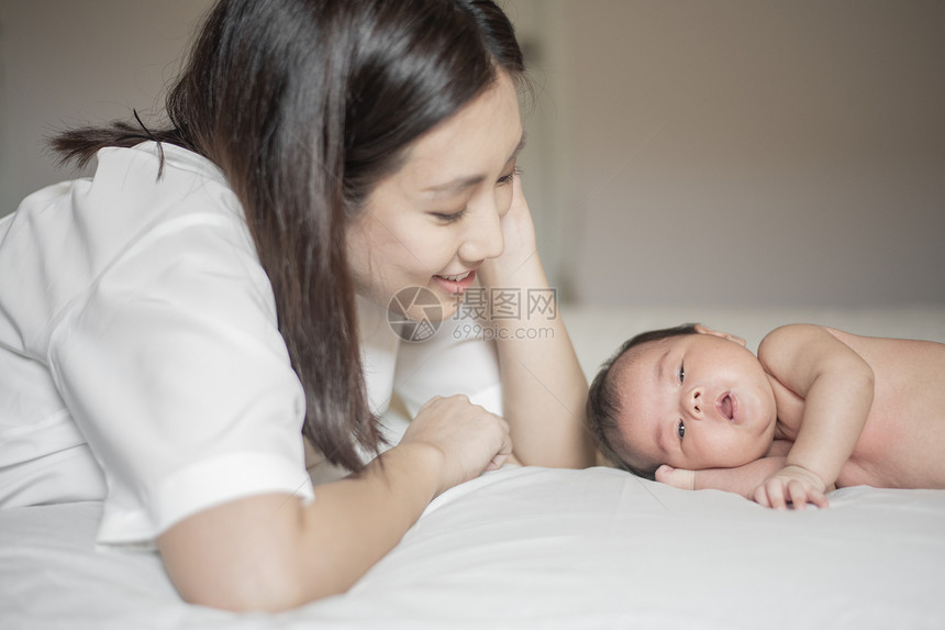 美丽的母亲正在卧室里玩弄她新生的婴儿图片