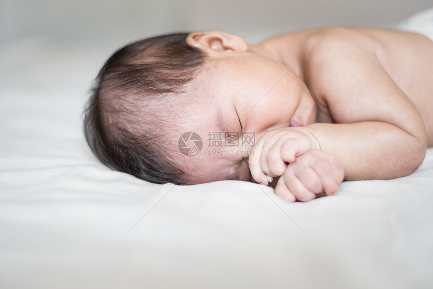 可爱的新生婴儿睡在白床上图片