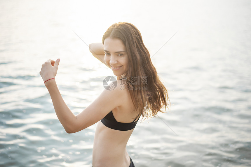 穿黑色比基尼的美女正在海滩上享受水图片