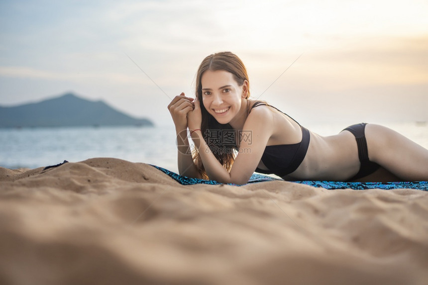 穿黑色比基尼的美女躺在沙滩上图片